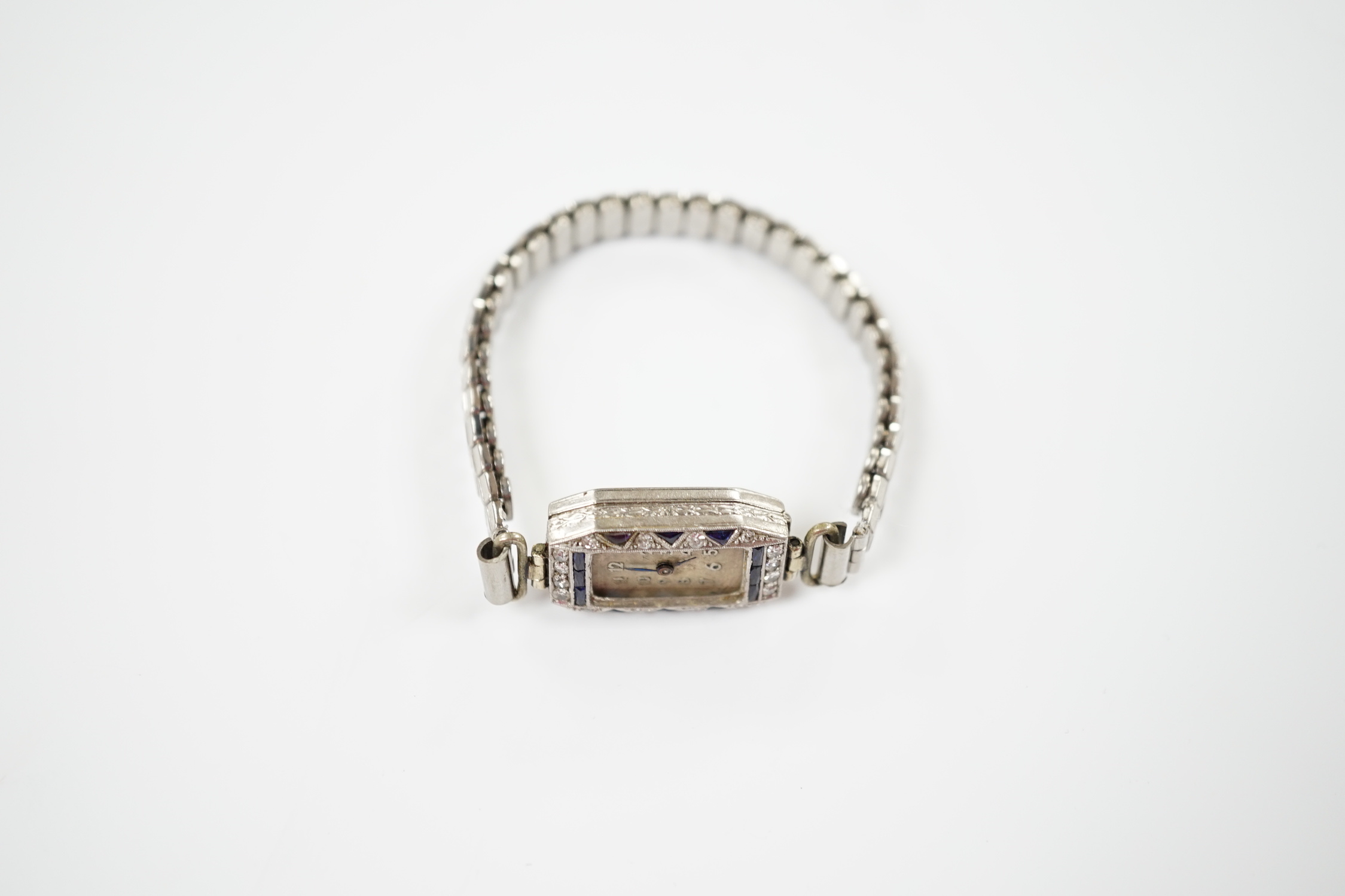 A lady's 1930's white metal (stamped platina), diamond and sapphire set manual wind cocktail watch (no glass or winding crown), on a stainless steel expanding bracelet.